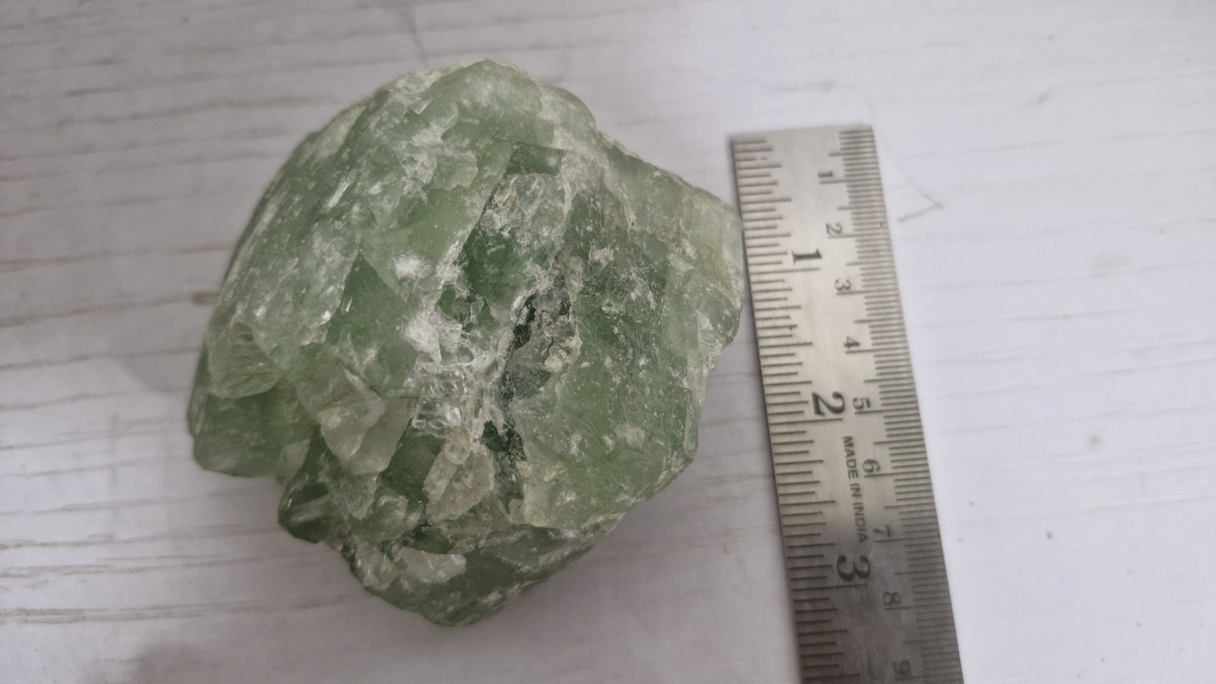 Green mineral specimen with a ruler for scale